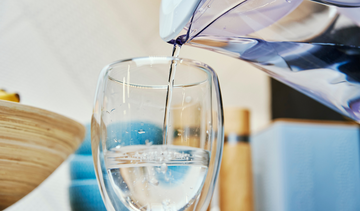 pouring water into a glass from a pitcher